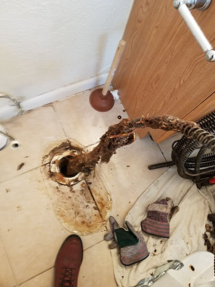 plumber pulling gunk out of a drain