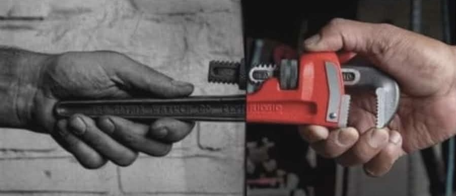 Hands working with a pipe wrench